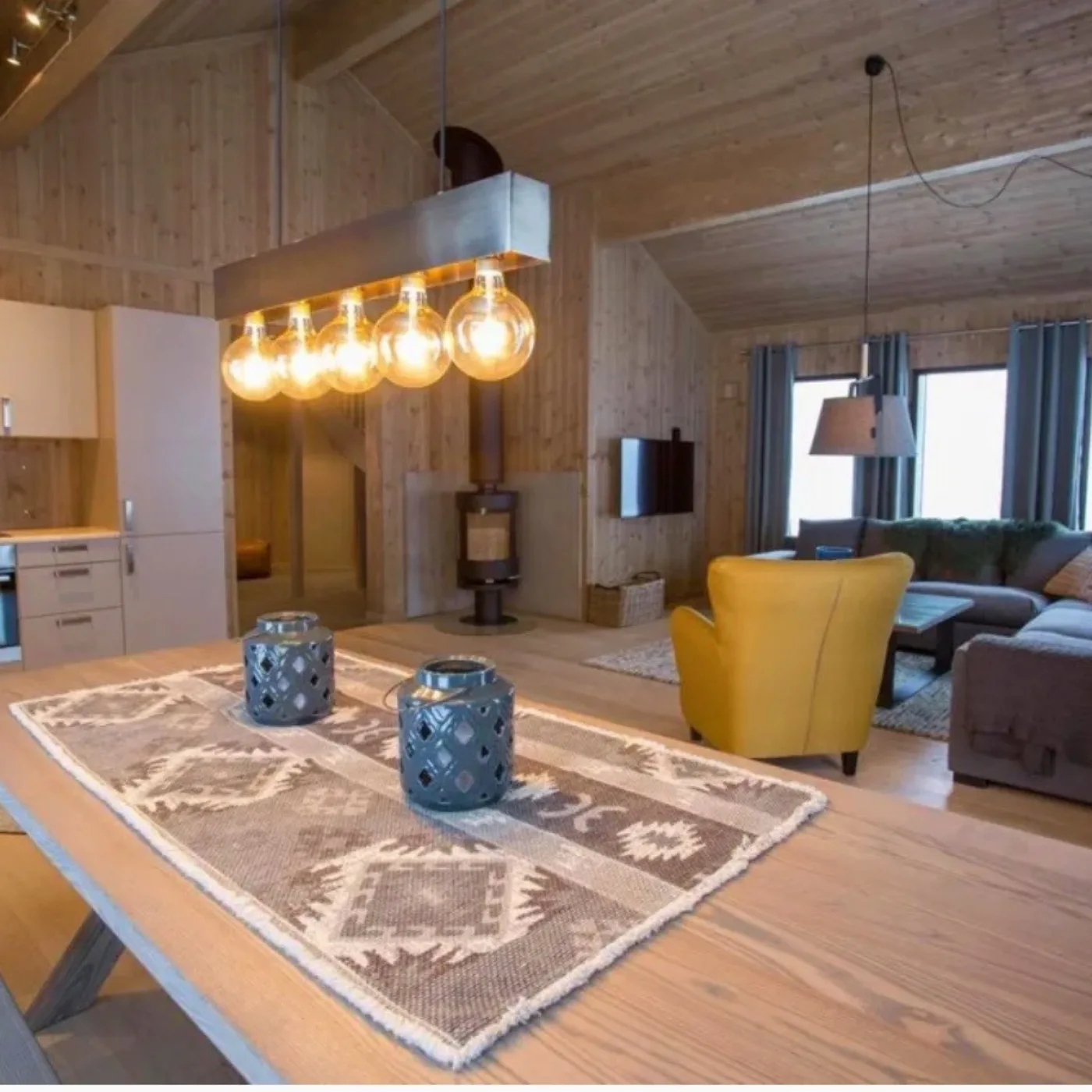 Vardagsrummet och köket med matsalsbord, braskamin och loungedel i hytterna i Slopestyle